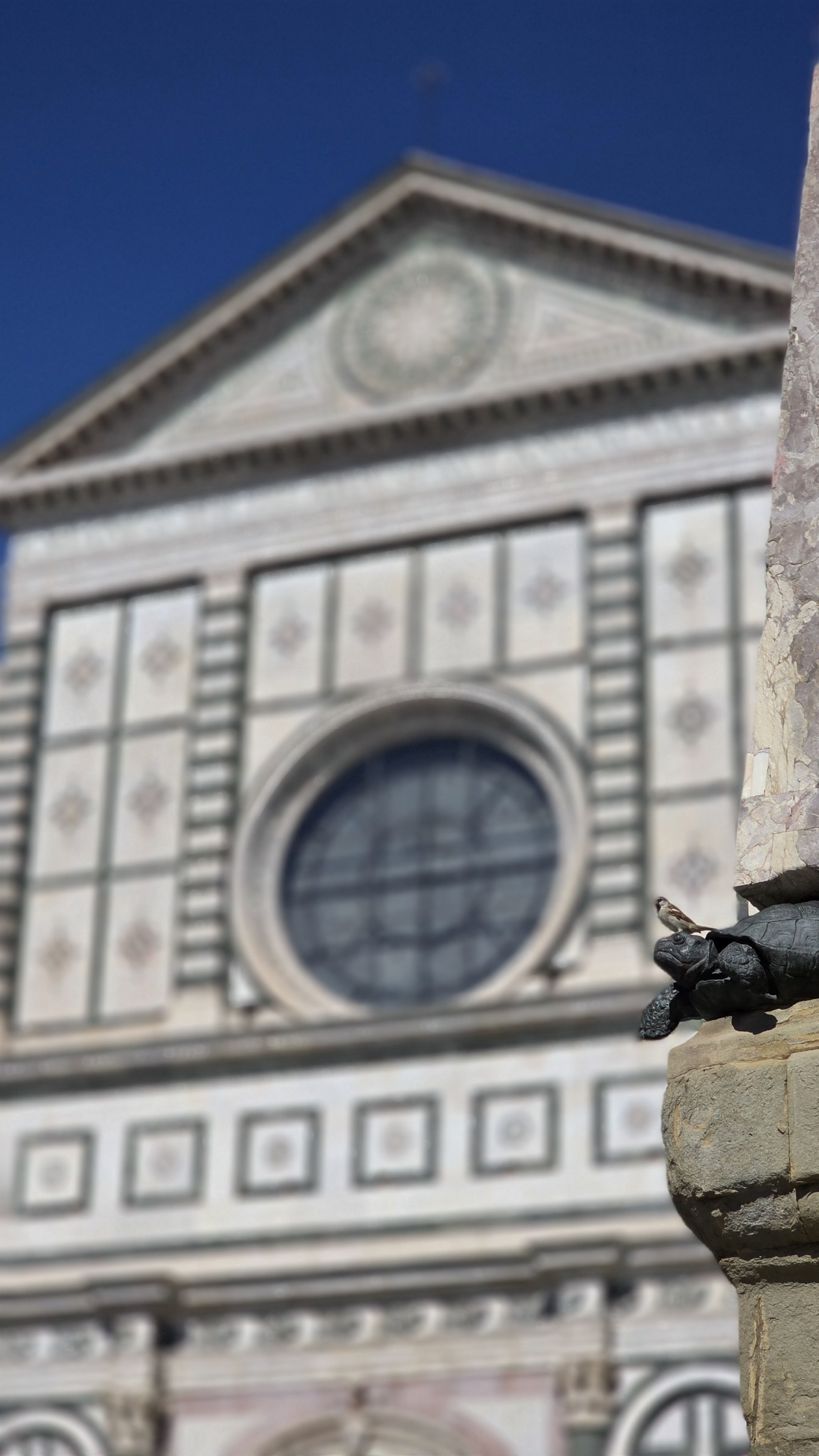 Green and white marble facade of Santa Maria Novella with a stone figure in front