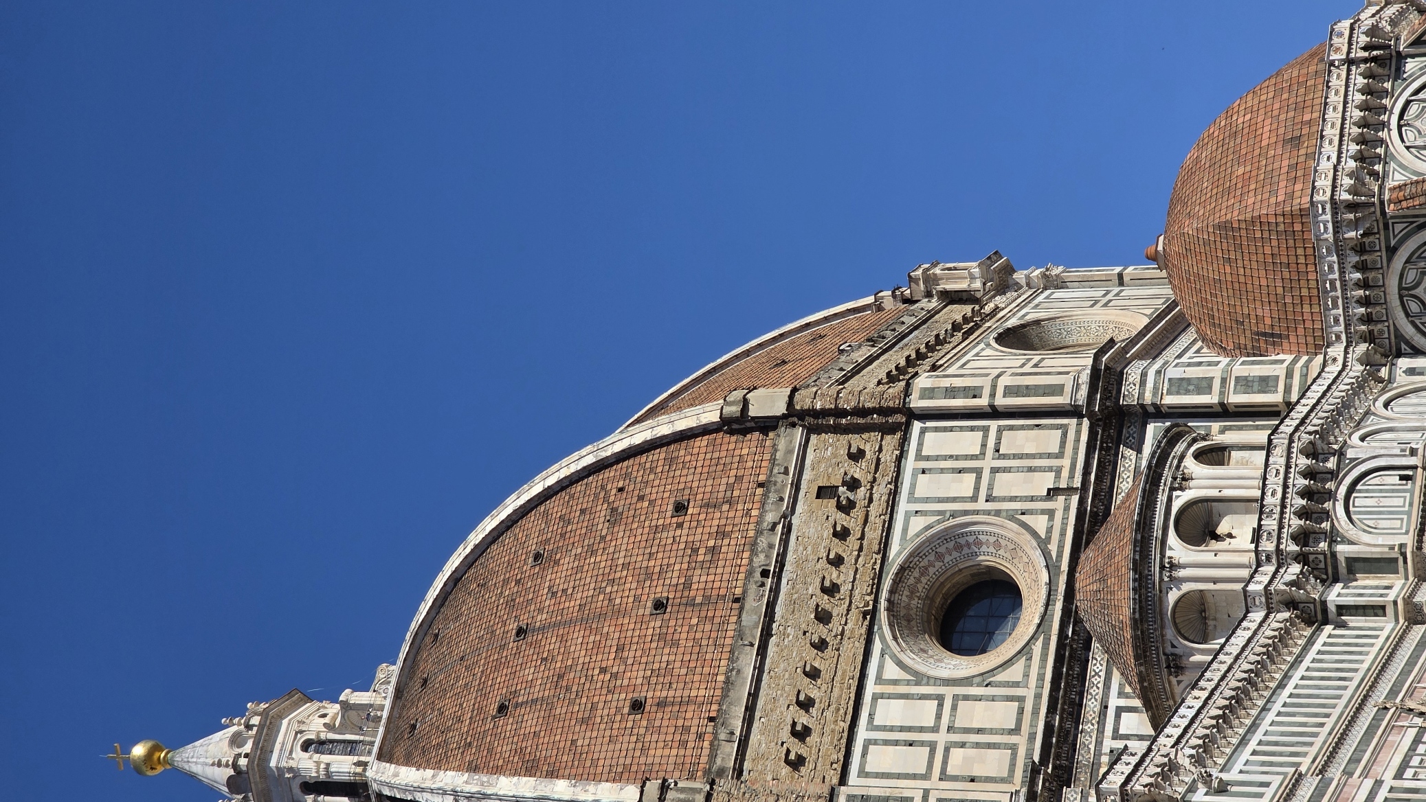 The brick dome and marble lantern of Florence Cathedral against a deep blue sky