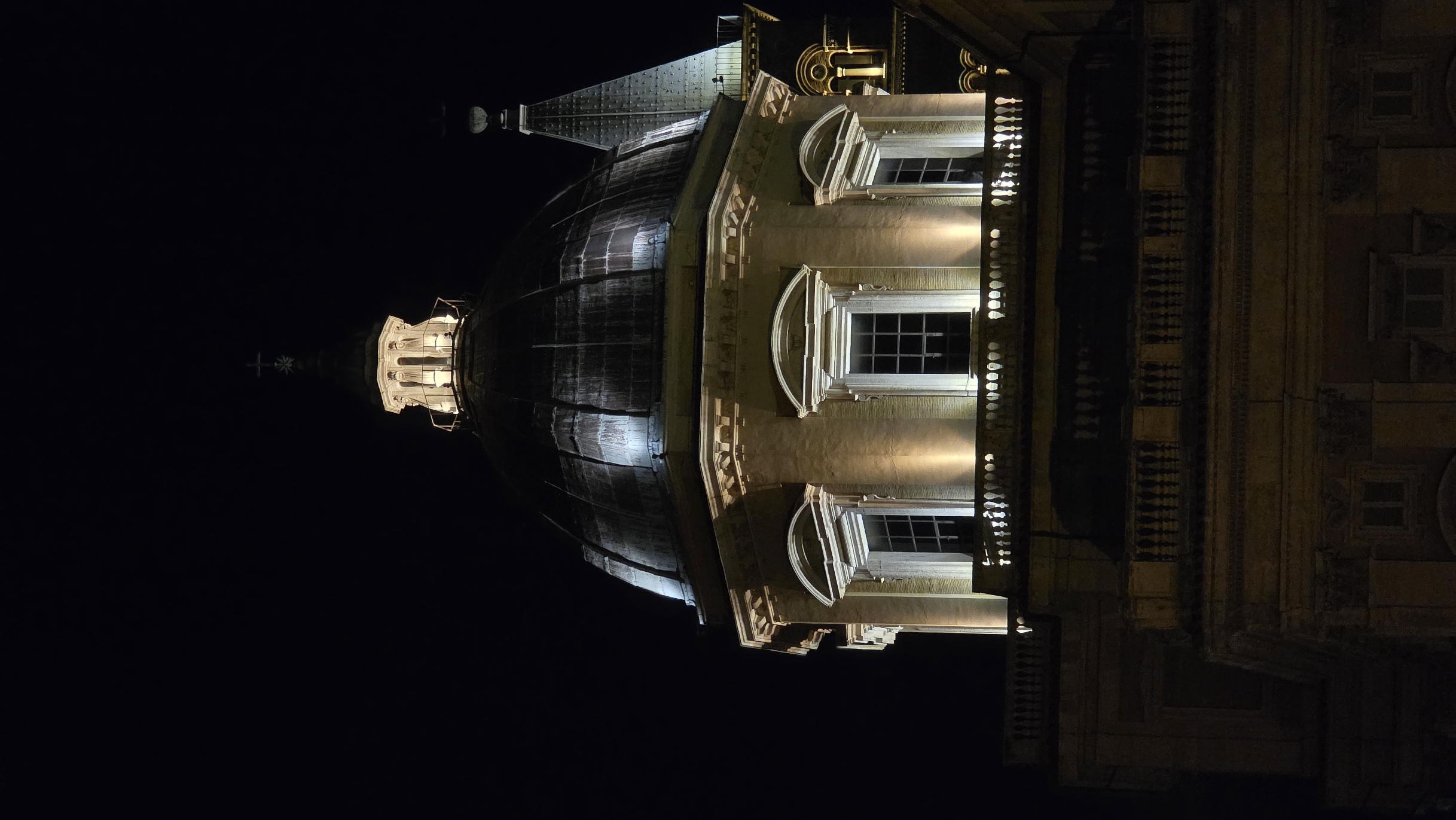 A floodlit church dome and lantern at night