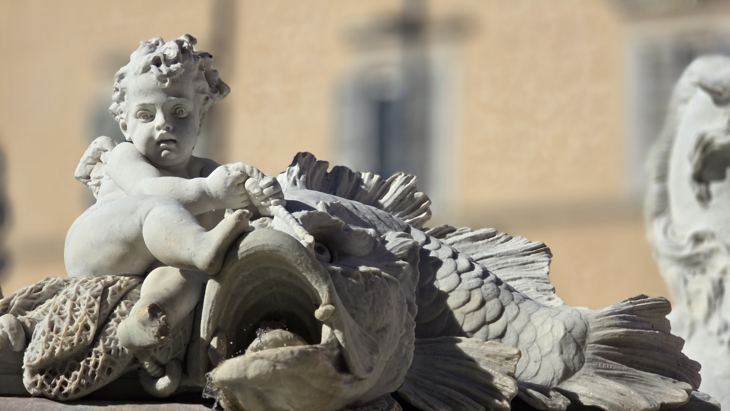 A fountain putto riding a dolphin, carved in white marble