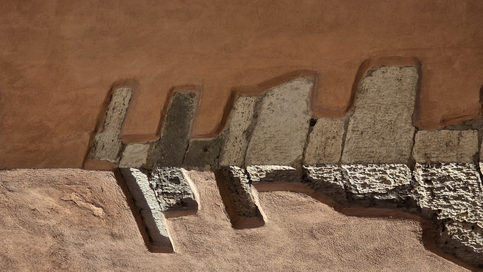 Brick teeth and stucco on a terracotta-coloured Roman wall