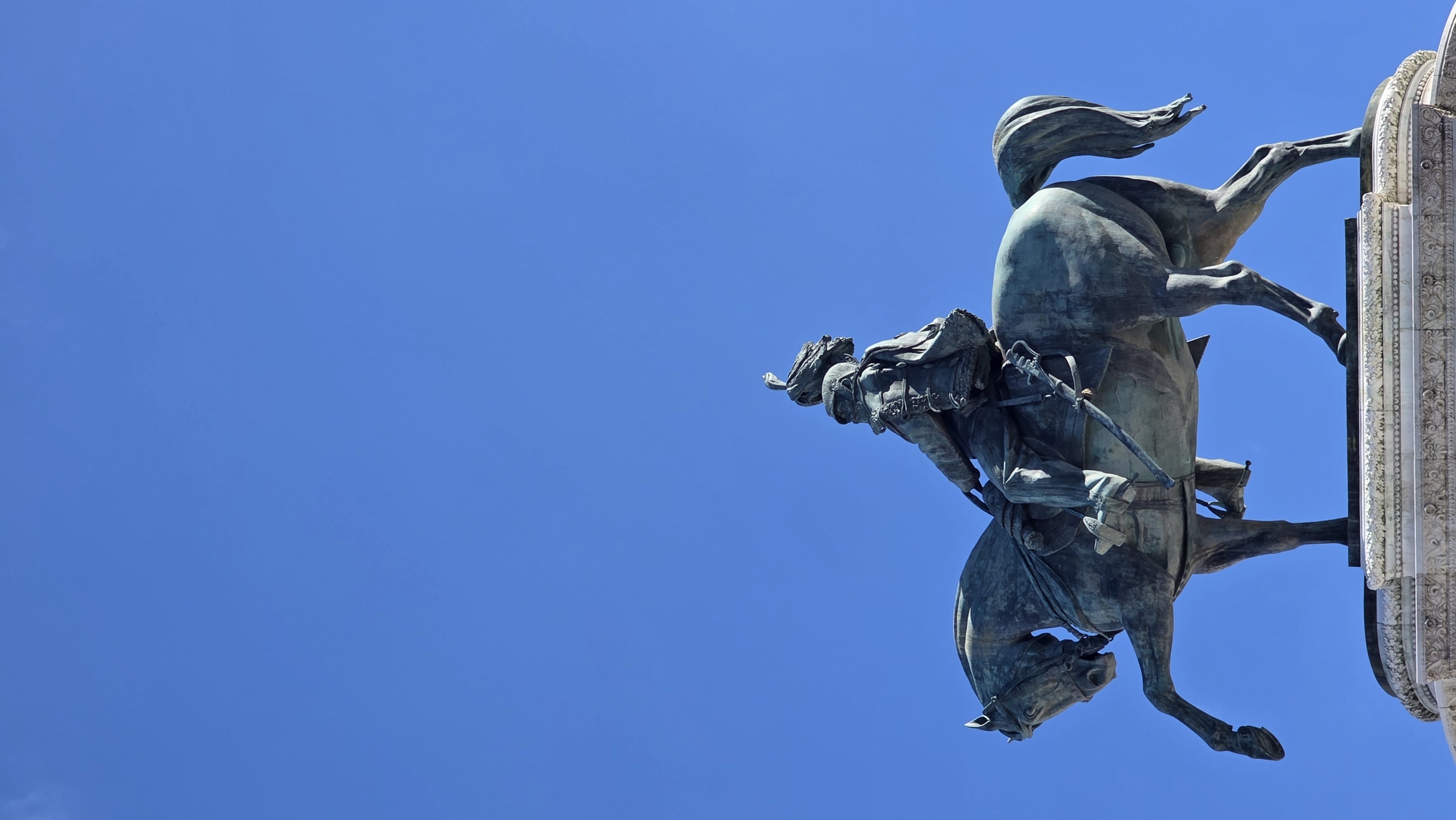 A bronze equestrian monument silhouetted on blue