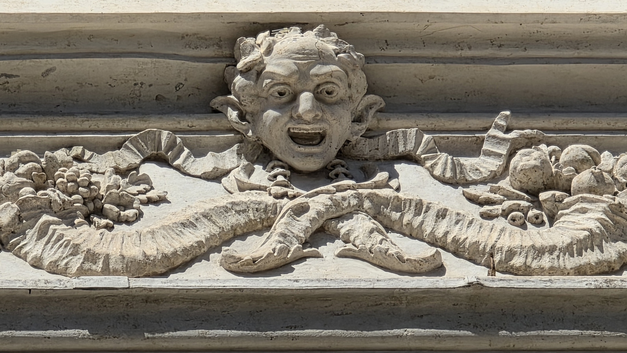 A carved mask and garland on a Roman entablature
