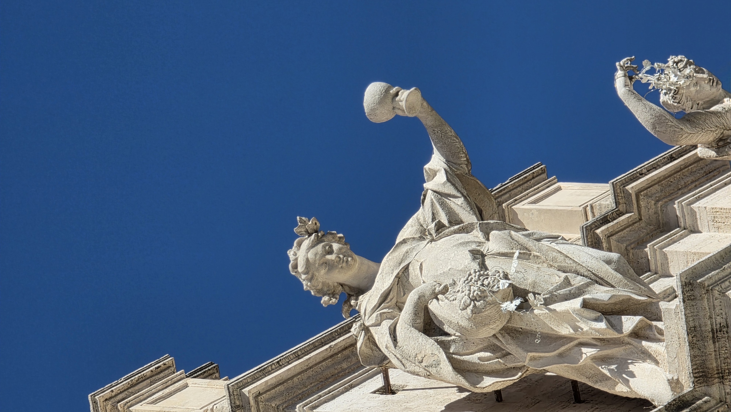 A baroque statue raised against a cloudless blue sky