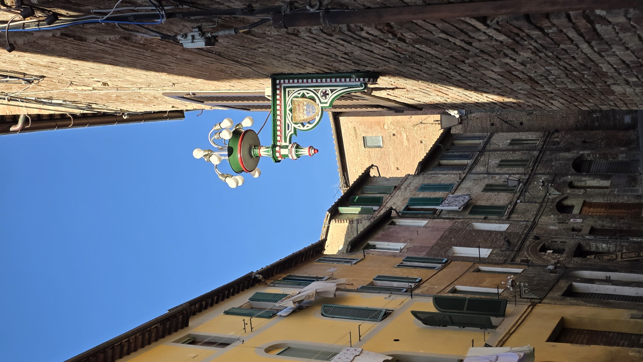 A narrow Siena lane with a wrought-iron sign and a window box of flowers