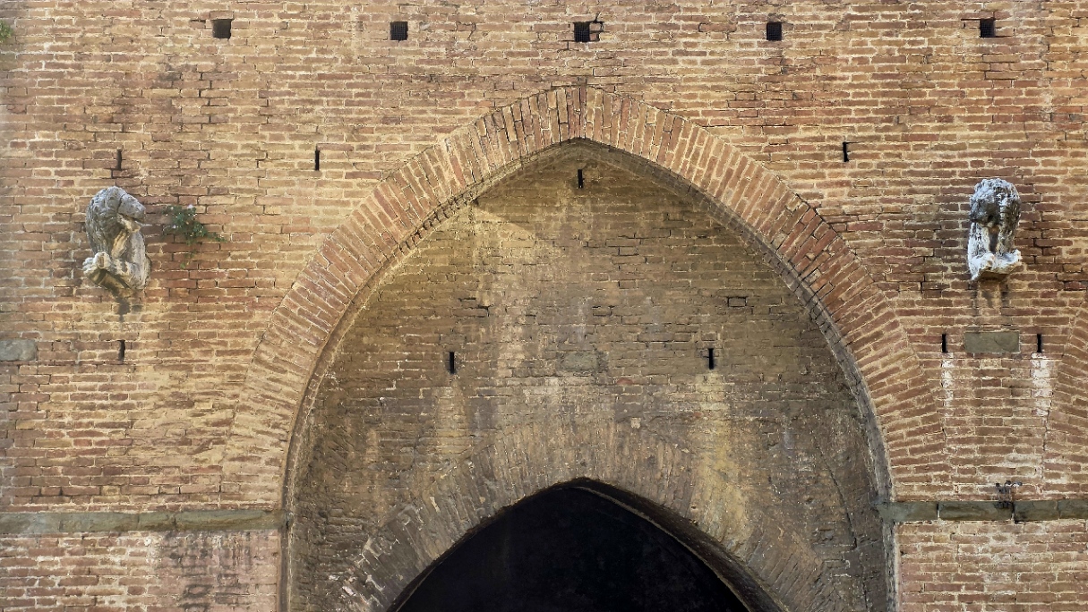 A pointed brick gateway arch in the walls of Siena