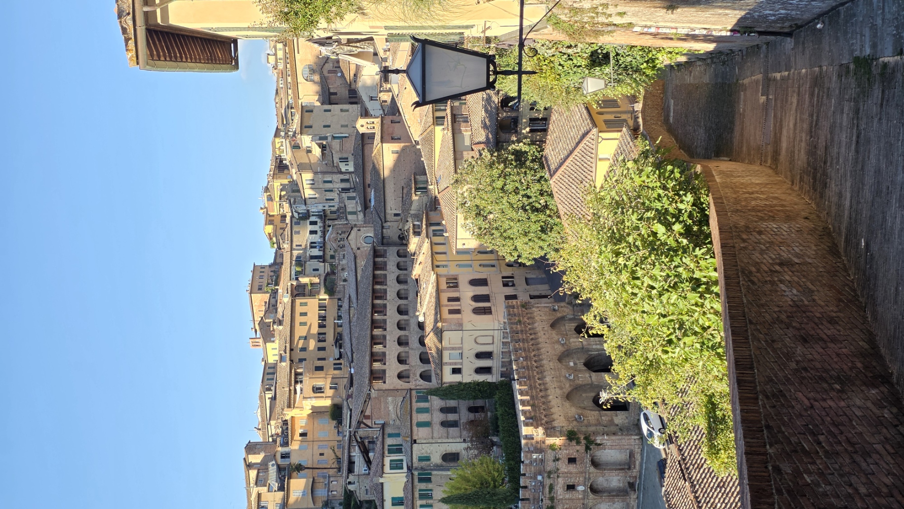 A walled lane looking out over the rooftops of Siena