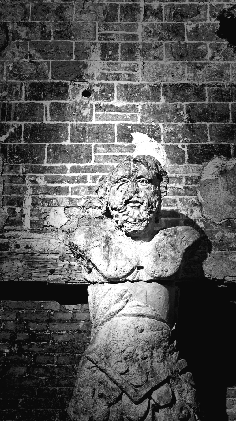 Black and white study of a carved figure set into a brick wall