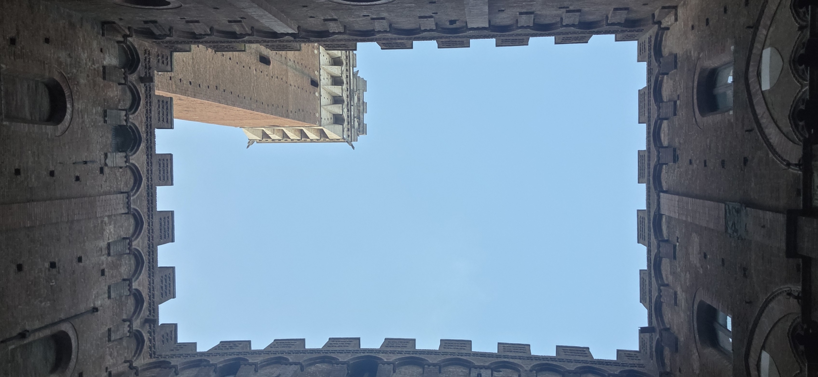 Looking up from a palace courtyard to a rectangle of pale sky