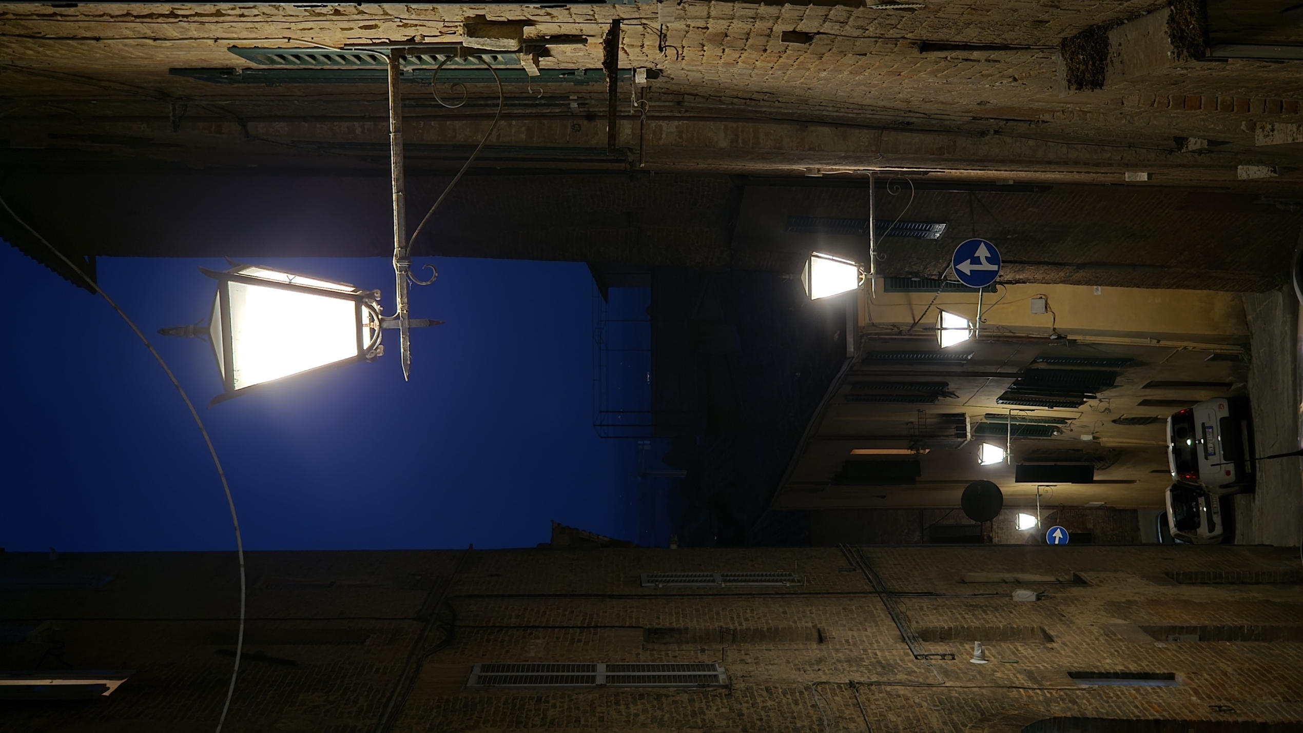 A single street lamp burning in an empty night lane