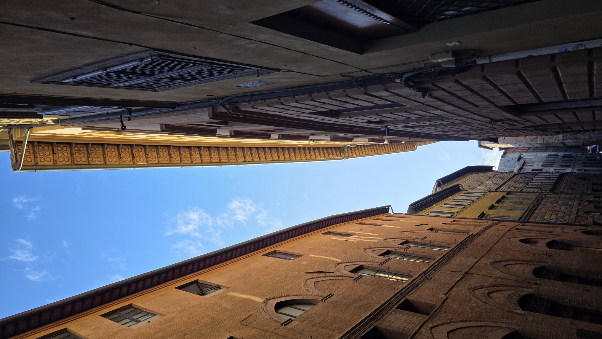 Warm brick housefronts in early sunlight along a Siena street