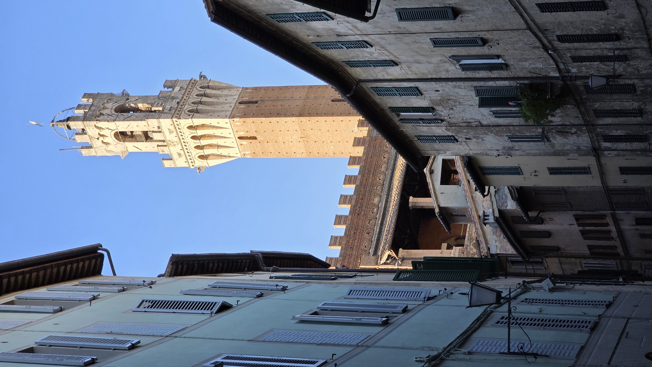 The Torre del Mangia seen at the end of a shadowed street
