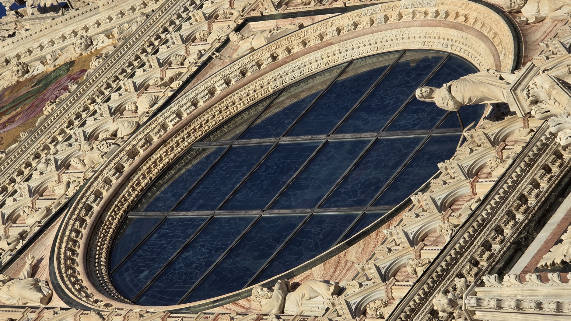 The carved rose window of Siena Cathedral in low evening sun